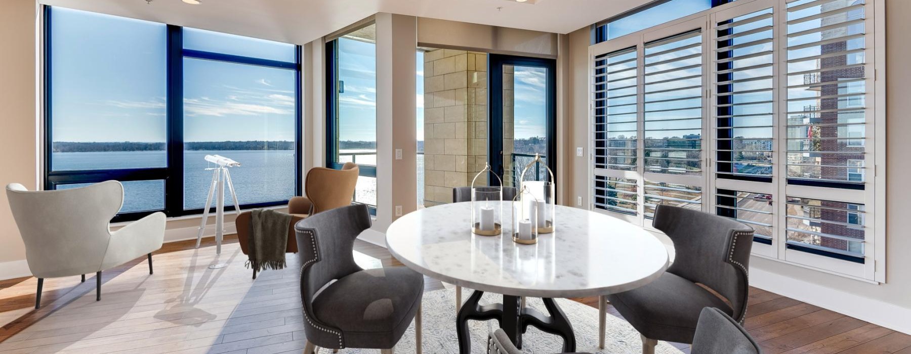 a room with a table chairs and a large window with a view of the lake