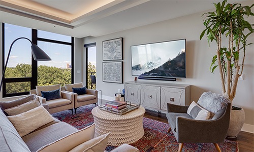 Spacious and well lit living room with wood floors and large windows 